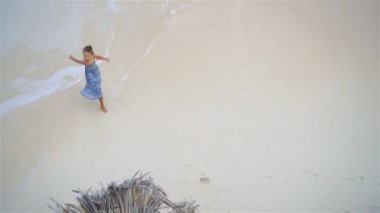 Sevimli küçük kız çok sığ suda eğleniyorum. Dan yukarıda turkuaz su ile ıssız bir Beach görüntülemek