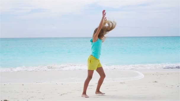 Petite fille active à la plage s'amusant beaucoup. Le gamin sportif fait le volant sur le bord de la mer. MOTION DE LENT — Video