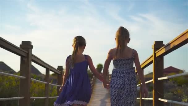 Niñas adorables en un puente de madera en la playa tropical blanca — Vídeos de Stock
