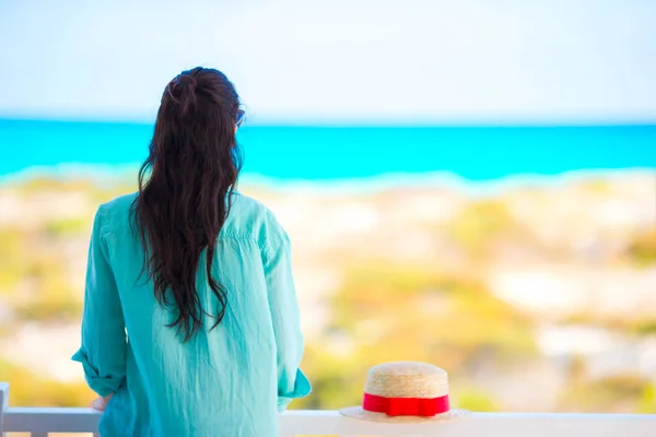 Ung kvinna på balkong med utsikt över en tropisk strand — Stockfoto