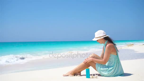 Mujer joven aplicar crema en sus suaves piernas bronceadas en la playa tropical — Vídeo de stock
