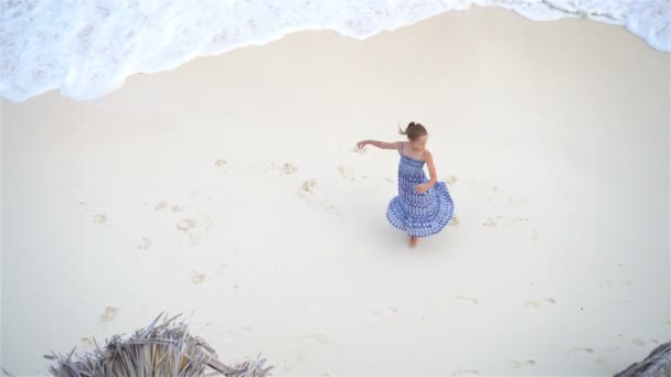 愛らしい少女が浅い水の楽しみの多くを持っていること。青緑色の水と人けのないビーチの上からの眺め — ストック動画
