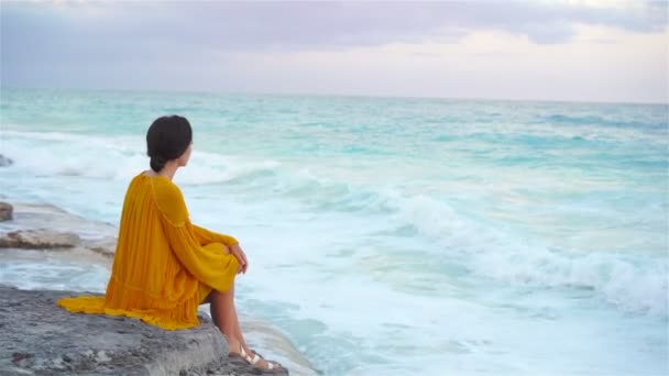 Young beautiful woman in sunset on the seashore. Happy girl in dress in the evening on the beach — Stock Video