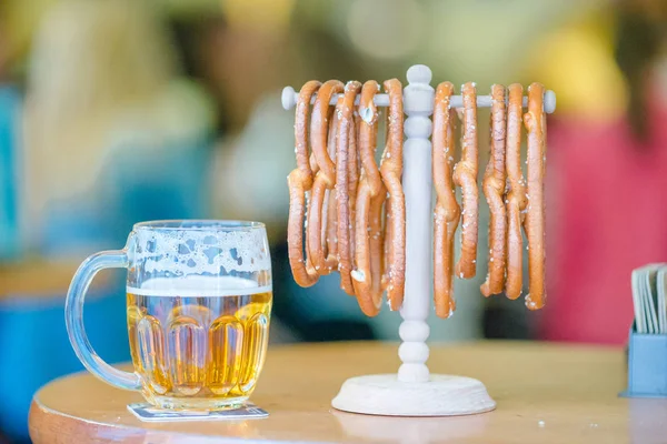 Chiudi pretzel morbidi salati e pinta di birra leggera su sfondo di legno . — Foto Stock