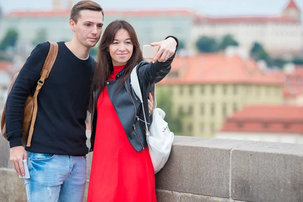 Pareja joven viajando de vacaciones en Europa sonriendo feliz. Caucásico familia haciendo selfie en popular karlov la mayoría — Foto de Stock