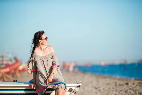 Joven hermosa mujer en la playa durante las vacaciones de verano. Chica sentada en el barco en la playa europea — Foto de Stock