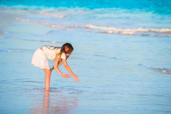 Adorável menina feliz na praia branca olhando para o oceano. Mar barulhento e um pequeno garoto bonito — Fotografia de Stock