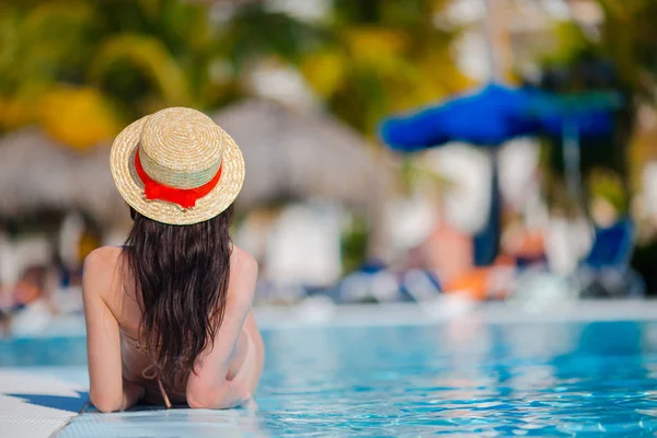 Hermosa joven que se relaja en la piscina. Vista trasera de la chica en la piscina al aire libre en el hotel de lujo — Foto de Stock