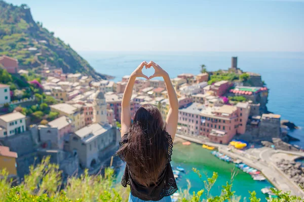 Beautiful girl making with hands heart shape on the old coastal town background of Vernazza, Cinque Terre National Park, Liguria, Italy, Europe — стоковое фото