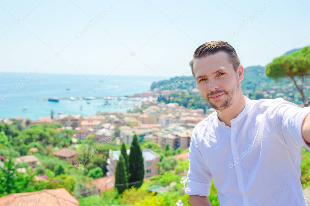 Happy young man taking selfie background the old coastal town of old italian city in Liguria