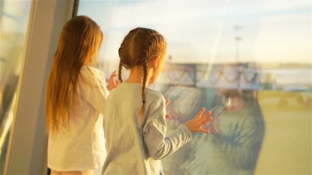 Девчонки у большого окна в аэропорту ждут посадки и смотрят на большой самолет. Медленное движение — стоковое видео