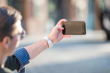 Erkek ellerinin yakın çekimi, sokakta cep telefonunu tutmaktır. Cep telefonu kullanan adam.