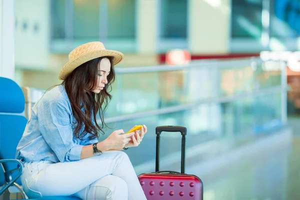 Νεαρή γυναίκα σε μια αίθουσα αναμονής αεροδρομίου, περιμένοντας πτήσης του αεροσκάφους. Καυκάσιος γυναίκα με έξυπνο κινητό τηλέφωνο στην αίθουσα αναμονής — Φωτογραφία Αρχείου