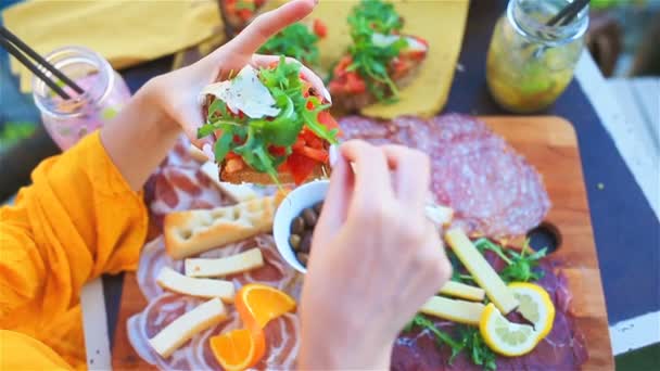 Ízletes olasz snack. Friss bruschettes, a sajt és a hús a táblán a szabadtéri kávézóban csodálatos kilátás olaszországi Manarola — Stock videók
