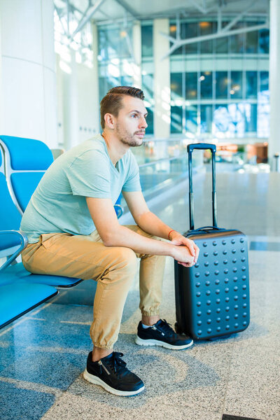 Young man in an airport lounge waiting for flight aircraft.