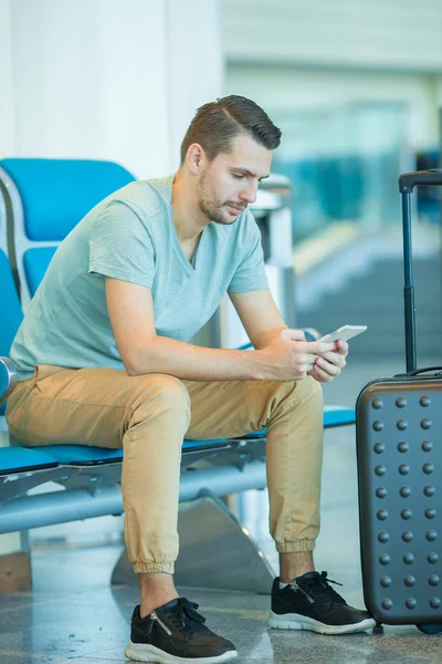 Passagier in een luchthaventerminal wachtend op vliegtuig. Jonge man met mobiele telefoon in de luchthaven wachten op de landing — Stockfoto