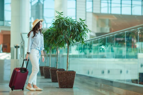 Giovane donna in cappello con bagaglio in aeroporto internazionale. Passeggero di una compagnia aerea in una lounge dell'aeroporto in attesa di un aereo di volo — Foto Stock