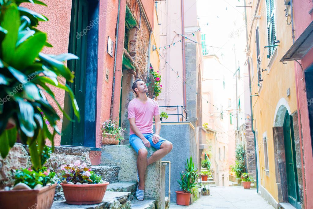 Young man tourist on holidays in Cinque Terre. Young caucasian guy walking at the old street in Vernazza