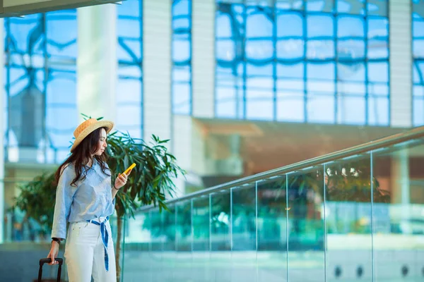 Feliz turista de chapéu com bagagem no aeroporto internacional. Passageiro da companhia aérea em um lounge do aeroporto esperando por aeronaves de voo — Fotografia de Stock