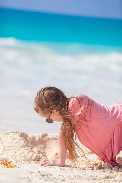 Очаровательная маленькая девочка играет с пляжными игрушками на белом тропиальном пляже — стоковое фото