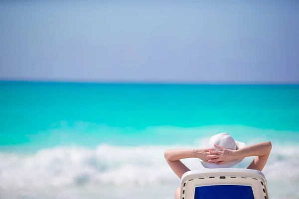 Ung kvinna i hatt på en tropisk strand, titta på det vackra havet — Stockfoto