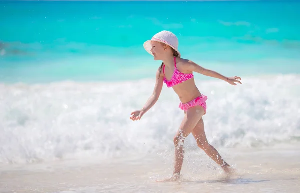Adorable niña en la playa teniendo un montón de diversión en aguas poco profundas —  Fotos de Stock