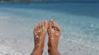 Kadın bacaklar beyaz plaj çakıl taşları ile. Beach Avrupa tatil Sardunya