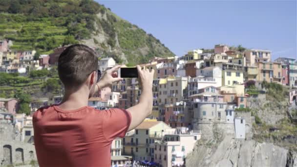 Młody człowiek zrobić zdjęcie z pięknym widokiem na starej wsi w Cinque Terre, Liguria, Włochy. Włoskie wakacje Europejskiej. — Wideo stockowe