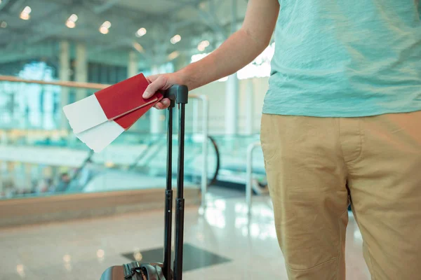 Primer plano de pasaportes con tarjeta de embarque y equipaje en manos masculinas en el aeropuerto. Turista viajando y esperando el avión —  Fotos de Stock