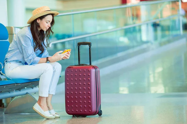 Mujer joven en un salón del aeropuerto esperando un aterrizaje en avión. Mujer blanca con smartphone en la sala de espera —  Fotos de Stock