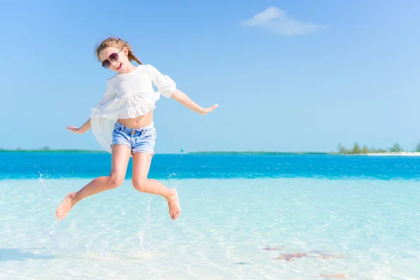 Increíble niña en la playa divirtiéndose mucho en las vacaciones de verano. Adorable niño saltando en la orilla del mar —  Fotos de Stock
