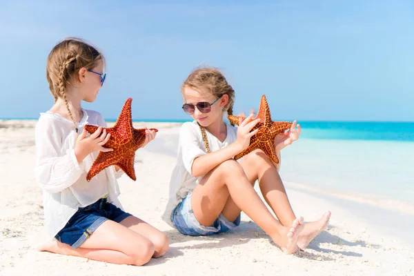 Adorables petites filles avec des étoiles de mer sur la plage blanche vide — Photo