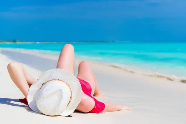 Young beautiful girl in hat lying on the beach at shallow tropical water — Stock Photo, Image