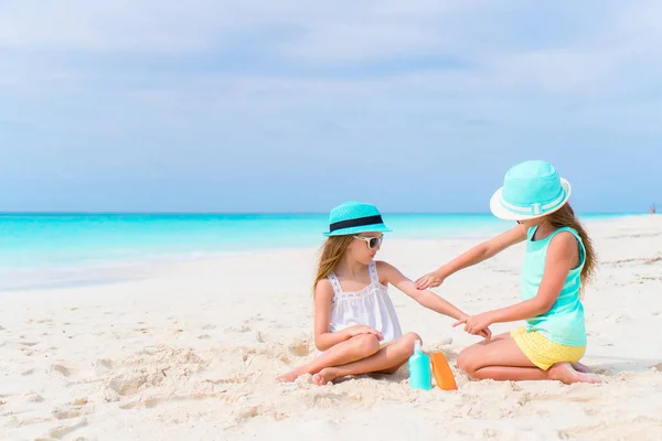子供たちはビーチでお互いに太陽のクリームを適用します。紫外線からの保護の概念 — ストック写真