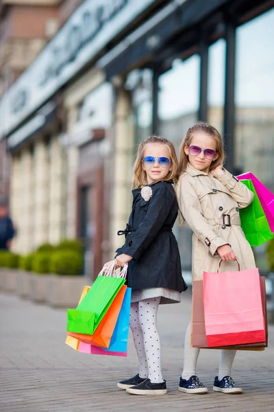 Adorable little girls with shopping bags walking in the city outdoors. Sales season in all over the world — Stock Photo, Image