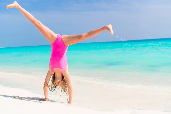 Petite fille active à la plage s'amusant beaucoup. Enfant sportif faisant la roue sur le bord de la mer — Photo