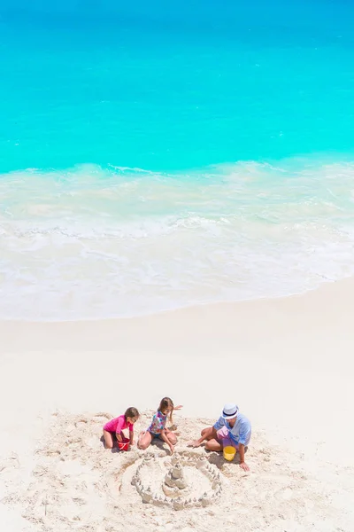 Otec a malé dcery, takže hrad z písku na tropické pláži. Pohled shora z rodiny hrát na pláži — Stock fotografie