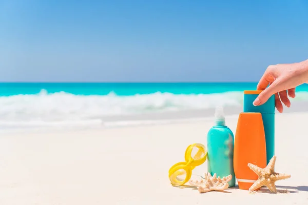 Suncream bottles, goggles, starfish on white sand beach background ocean — Stock Photo, Image