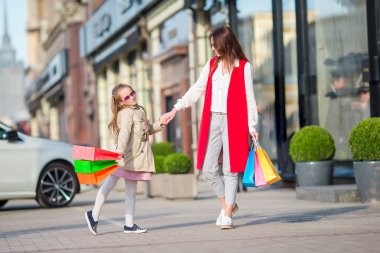 Sevimli küçük kız ve mutlu anne ile alışveriş torbaları Europe açık havada yürüyüş