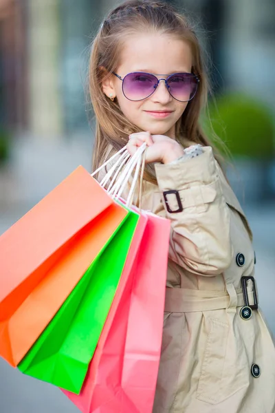 Alışveriş torbaları açık havada ile sevimli küçük kız portresi. Moda yürümeye başlayan çocuk Avrupa şehri açık havada — Stok fotoğraf