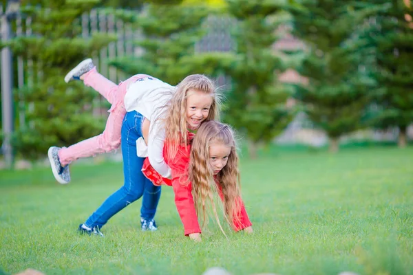 Meninas felizes estão se divertindo ao redor em um gramado verde — Fotografia de Stock