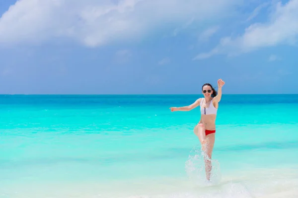 Giovane donna su una spiaggia tropicale spruzzi in acque poco profonde — Foto Stock