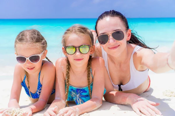 Madre y niñas tomando selfie en la playa tumbadas en arena blanca. familia feliz tomar selportrait relajarse en vacaciones —  Fotos de Stock