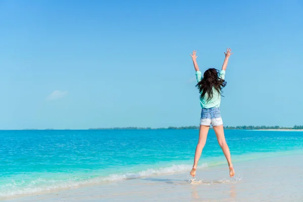 Молода жінка стрибає і піднімає руки на пляжі з білим піском — стокове фото