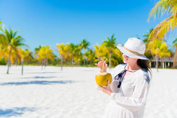 Mujer joven bebiendo leche de coco en un día caluroso en la playa . — Foto de Stock