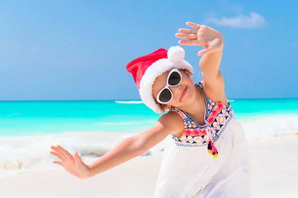 Menina adorável em chapéu de Santa durante as férias na praia de Natal — Fotografia de Stock