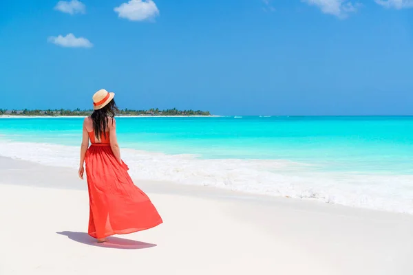 Mooie jongedame aan tropische kust. Achteraanzicht van een jong meisje in de rode jurk achtergrond de zee — Stockfoto