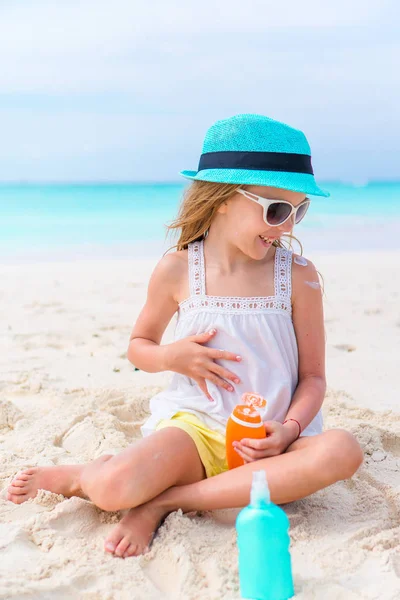 Rozkošná holčička s suncream láhev na pláži — Stock fotografie