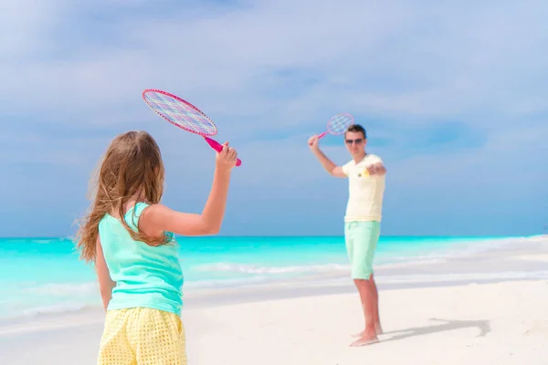 Little girl playing tennis with father on white tropical beach — Stock Photo, Image