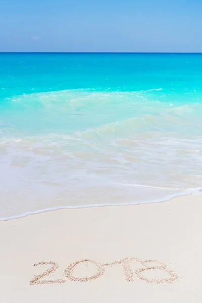 Mão de ano 2018 escrita sobre a areia branca em frente ao mar — Fotografia de Stock